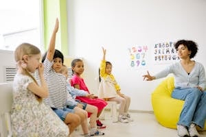 Teacher Giving Lesson and Children Raising Their Hands