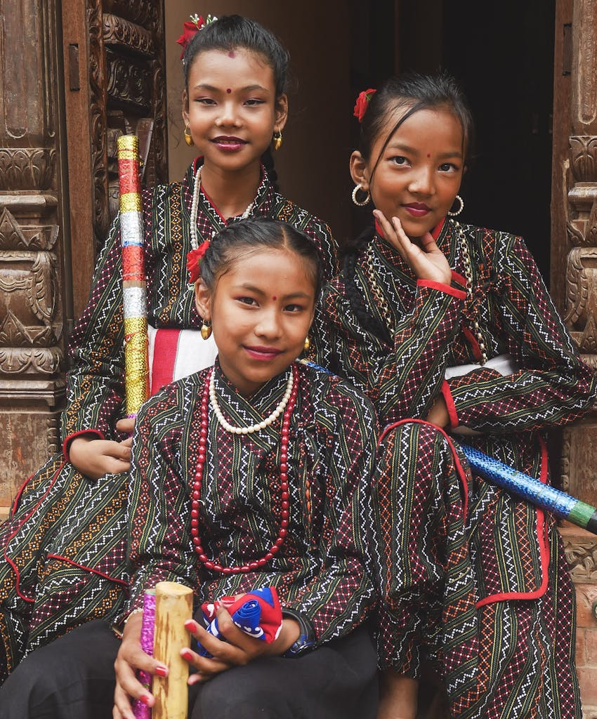 Three young girls in traditional clothing pose for a photo