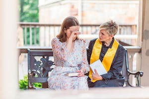 Woman in White Floral Dress Sitting on Bench with a Priest