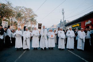 A group of priests in white robes walking down a street