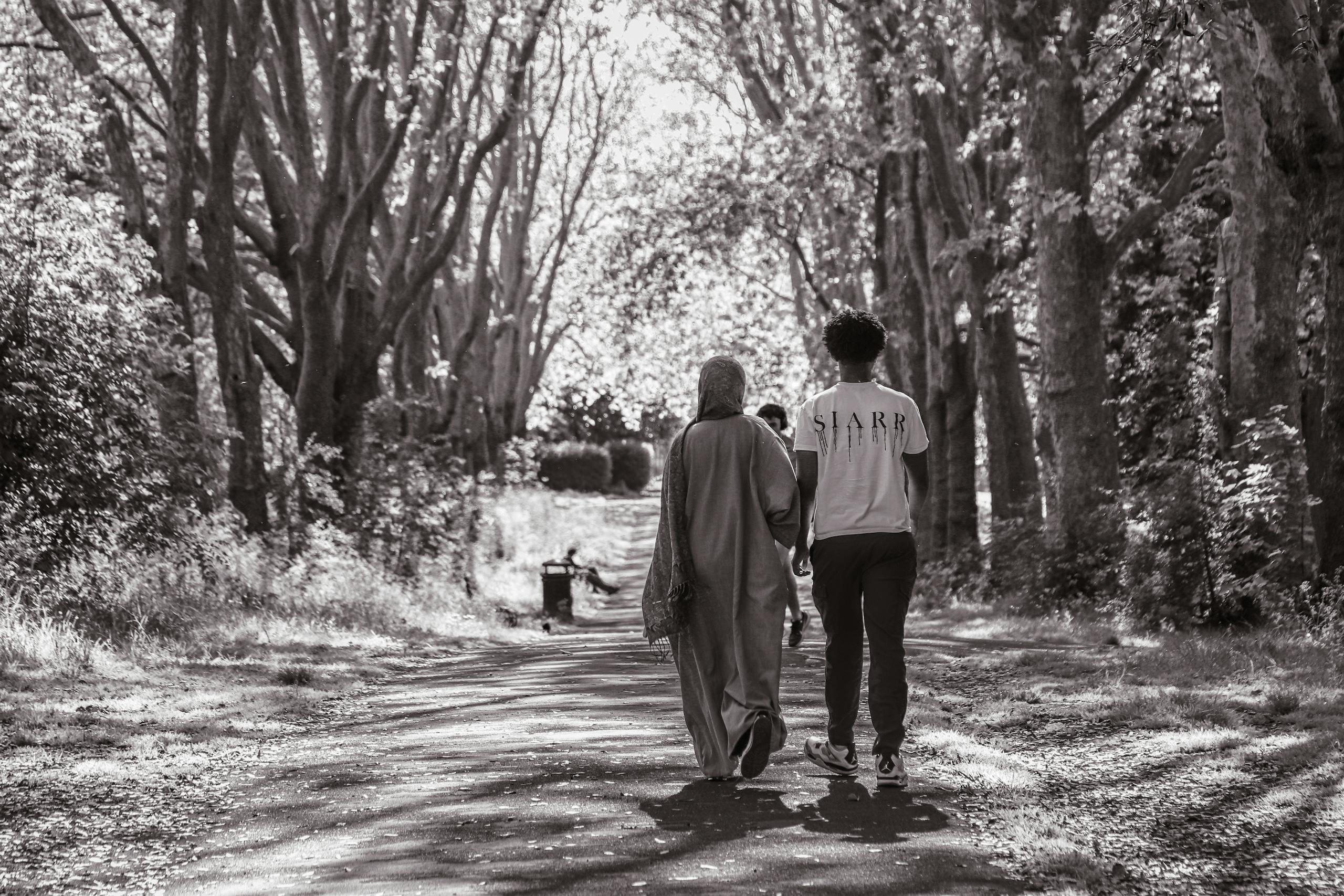 Two people walking down a path in the woods